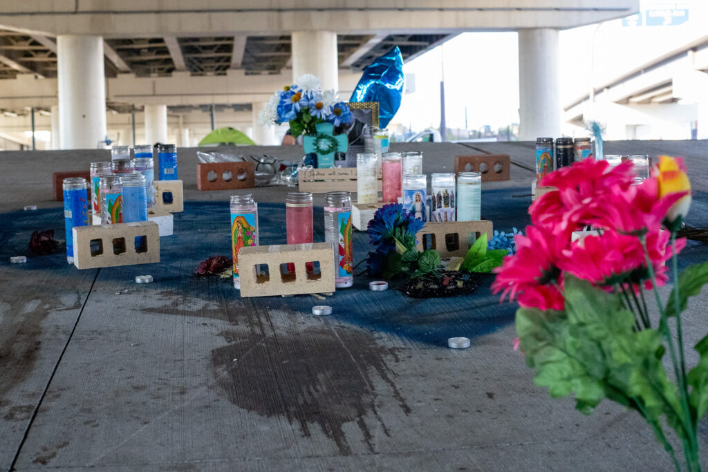 Photograph of a shrine to Lucas Cordero who was shot on the 2400 block of Aramingo. Plastic flowers, prayer candles, votive candles, and other messages are arranged inside a large blue heart spray-painted on the ground.